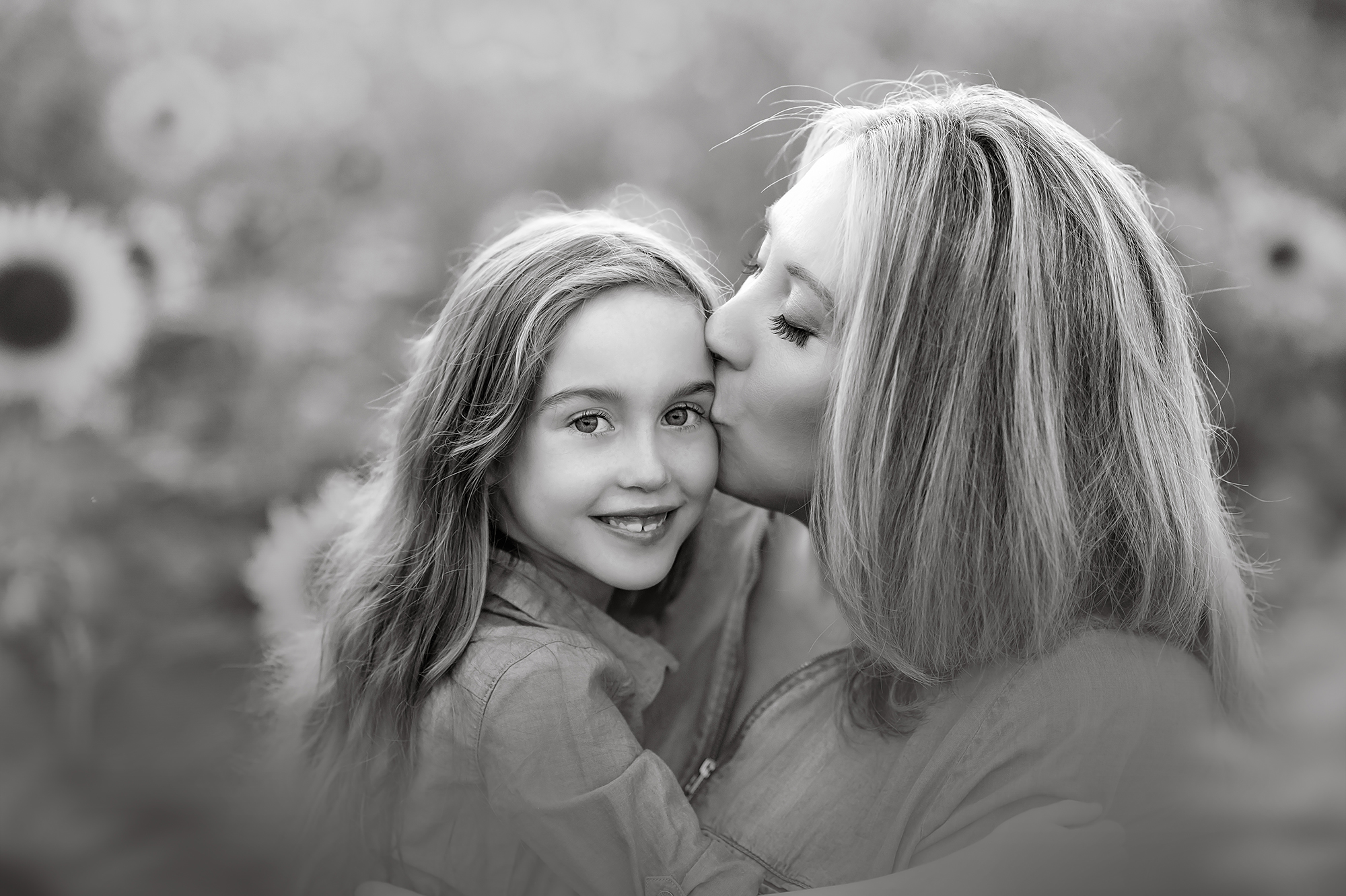 Mother kisses daughter in black and white portrait